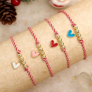 Detail of four handmade woven bracelets with heart charms and festive red white ropes