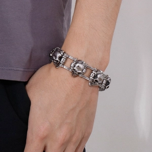 Detailed view of silver skull chain bracelet on wrist showing punk motorcycle style