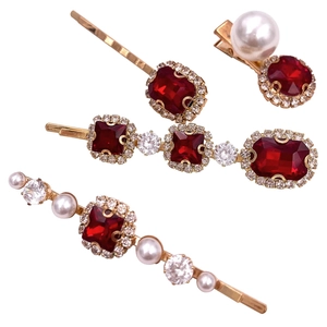 Detailed view of vintage gold hairpins with red gems, white pearls and clear crystals