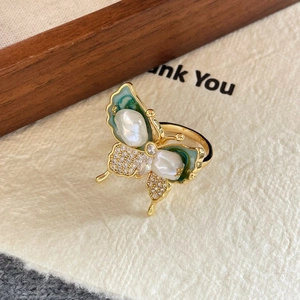 Detailed close-up of a butterfly ring with gold plating, pearls and green enamel