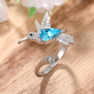 Macro-opname van kolibrie-ring met lichtblauwe druppelsteen en witte diamanten