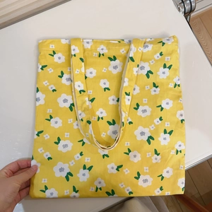 Detailed view of yellow floral canvas tote bag with white daisy patterns and sturdy straps