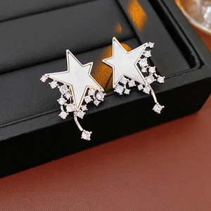 Close-up of star earrings with white mother of pearl and dangling cubic zirconia tassels