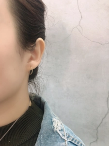 Close-up of minimalist small gold hoop earrings on model with casual daily outfit