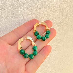 Detail of hand-held gold hoops with green malachite beads in a French vintage style