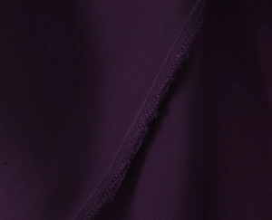Macro view of dark purple chiffon fabric showing precise overlock stitching and texture
