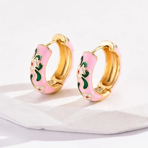 Detail of pink enamel hoop earrings with floral patterns on a white marble display