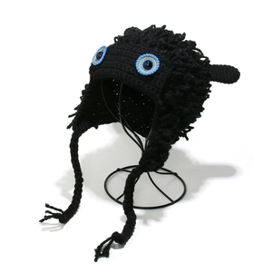 Detail of handmade crochet monster beanie with blue eyes and braided earflaps