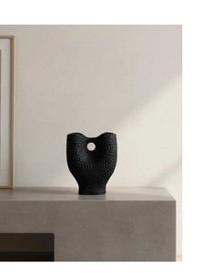 Vue détaillée d'un vase en céramique noire à texture martelée et forme organique moderne