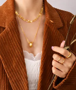 Detail of layered gold necklaces and rings set on a model wearing a brown velvet blazer