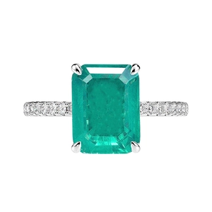 Emerald cut green emerald ring with side diamonds on polished white gold band