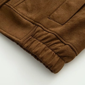 Detail of the elastic hem on a brown suede biker jacket with premium matte texture