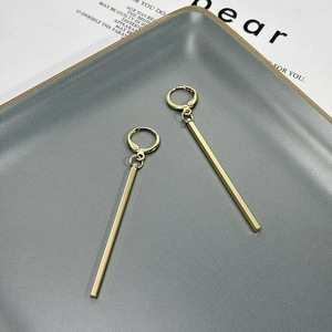 Macro shot of minimalist gold long geometric bar earrings on a stylish matte tray