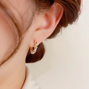 Detail of C-shaped gold pearl earrings featuring wrapped seed pearls on gold metal wires