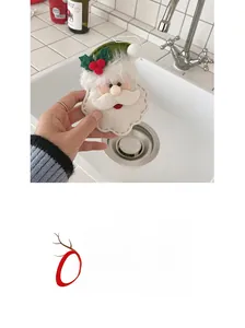 Detail of a handmade red and white felt Santa ornament with green leaf and gold hanging cord