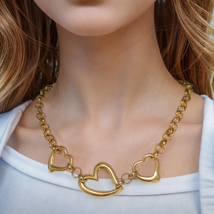 Modern gold necklace featuring three hollow heart pendants worn on a model's neck
