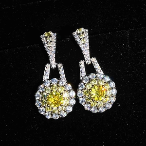 Close-up of yellow crystal earrings with white zircon settings on black velvet