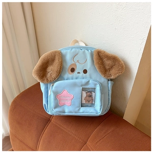 Detail of cute puppy backpack in sky blue with plush ears and star patch on a chair