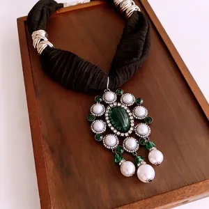 Vintage necklace with large emerald green oval pendant and pearl accents on black fabric cord