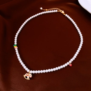 Détail d'un collier de perles avec un cheval à bascule en émail rose et pendentif coeur rouge