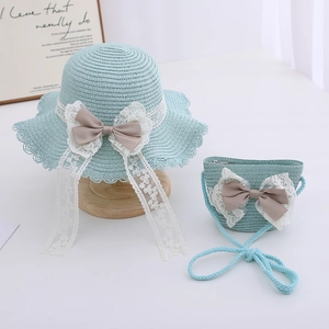 Close-up of children's straw hat and matching bag with lace trim and large brown bow