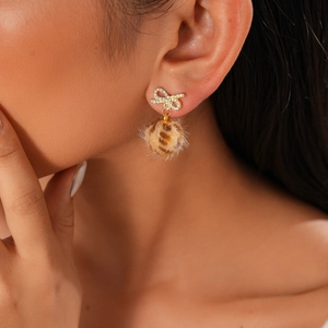 Detail of leopard print pom pom earring with crystal bow on model for winter fashion