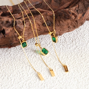 Gold emerald necklace with rectangular gemstone pendant and engraved baby charm