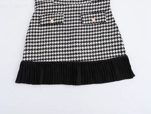 Détails de la robe en tweed à motif pied-de-poule avec boutons dorés et ourlet plissé noir
