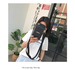 Close-up of black nylon crossbody phone bag with adjustable strap and golden logo detail