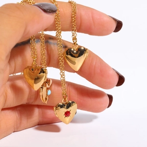 Detailed close-up of golden heart locket necklaces with birthstone accents in hand