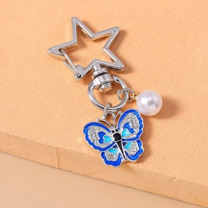 Detail of blue enamel butterfly keychain with sparkling rhinestones and a white pearl charm