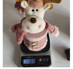 Pink reindeer plush Christmas gift box weighing 107g on a digital scale