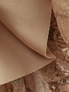 Gros plan sur la dentelle beige montrant la doublure en tricot et la texture fine