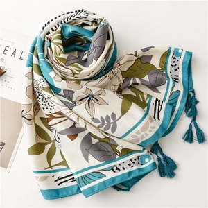 Detailed view of silk scarf with floral prints, teal borders and tassel ornaments