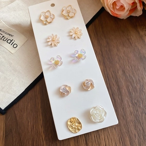 Detailed set of floral stud earrings featuring crystal roses and pearls on display