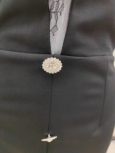 Détail macro d'une robe en dentelle noire avec bouton cristal et pendentif Saturne