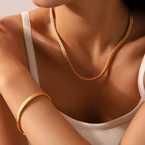 Close-up of 18K gold-plated braided chain necklace and bracelet on model