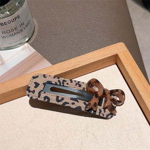 Close-up of leopard print BB hair clip featuring a brown resin bow on a textured background
