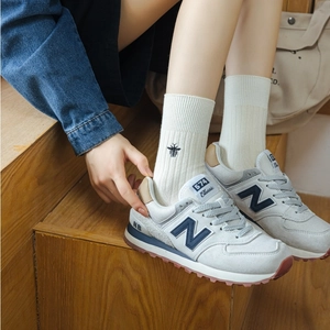 Detailed view of white vertical striped cotton socks with black bee embroidery on the ankle