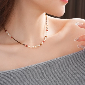 Detailed shot of tiger eye stone and freshwater pearl necklace on a model collarbone