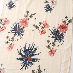Close-up of beige cotton linen scarf with blue and orange floral print and striped border