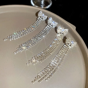 Detailed macro shot of silver bow tassel earrings with zircon inlay on a round tray