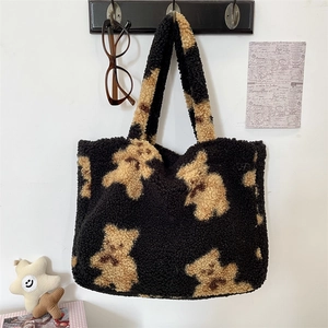 Close-up of cute beige bear pattern on a black plush tote bag with soft lambskin texture