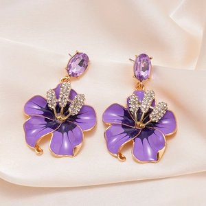 Dettaglio di orecchini a fiore viola con petali smaltati e brillanti strass al centro
