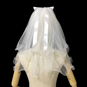 Detail of white bridal veil with double layers, pearl accents, and a satin ribbon bow