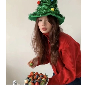 Close-up of green Christmas tree hat with colorful balls and red knit cardigan sweater