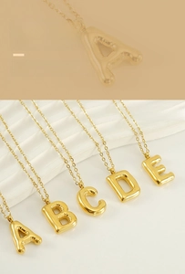 Détail des colliers avec pendentifs lettres bulles 3D dorées A-E en finition polie brillante