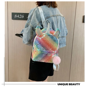 Detail view of a sparkly rainbow sequin unicorn backpack with a pink furry pompom charm