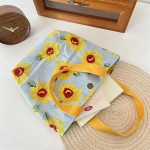 Detail of light blue sunflower tote bag with yellow handles and metal snap closure