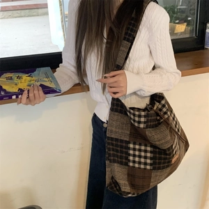 Dettaglio della grande borsa hobo a quadri con coulisse indossata da una modella donna